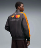 Model wearing a black and orange motorsport-inspired bomber jacket from the back